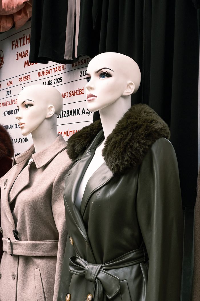 Mannequins showcasing elegant winter coats in an outdoor street market setting.